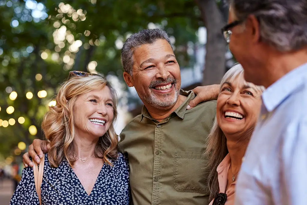 An image of 4 elderly adults hugging each other and talking about their future in 55+ apartments for seniors.